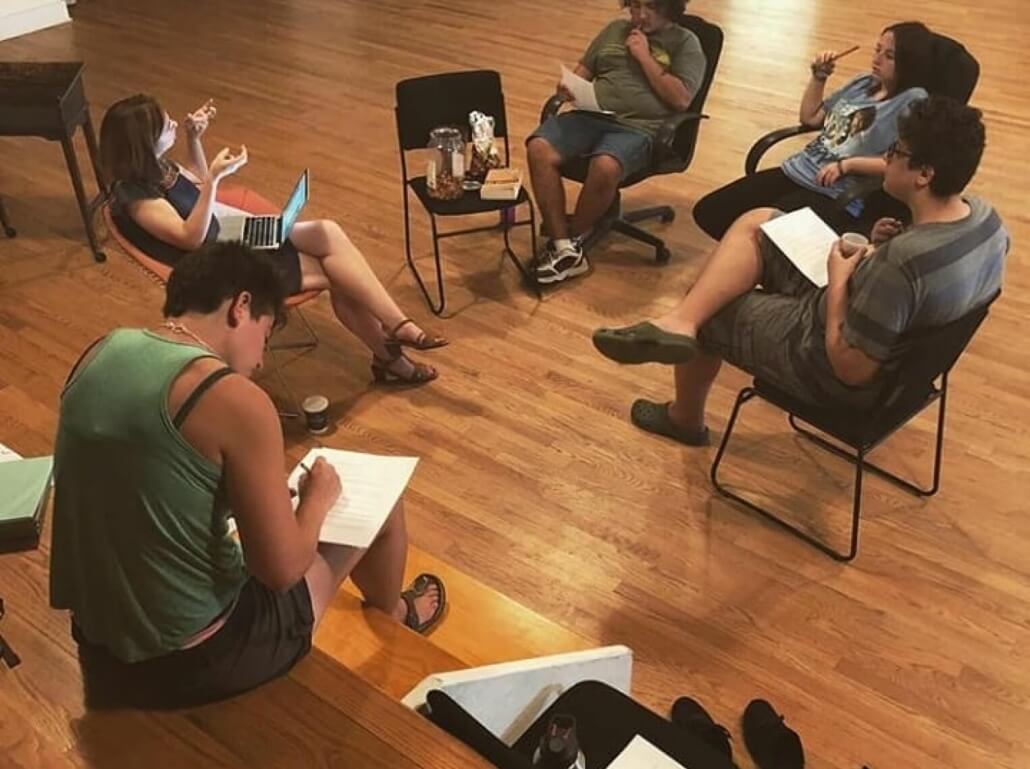 A group of young playwrights sitting in a circle brainstorming