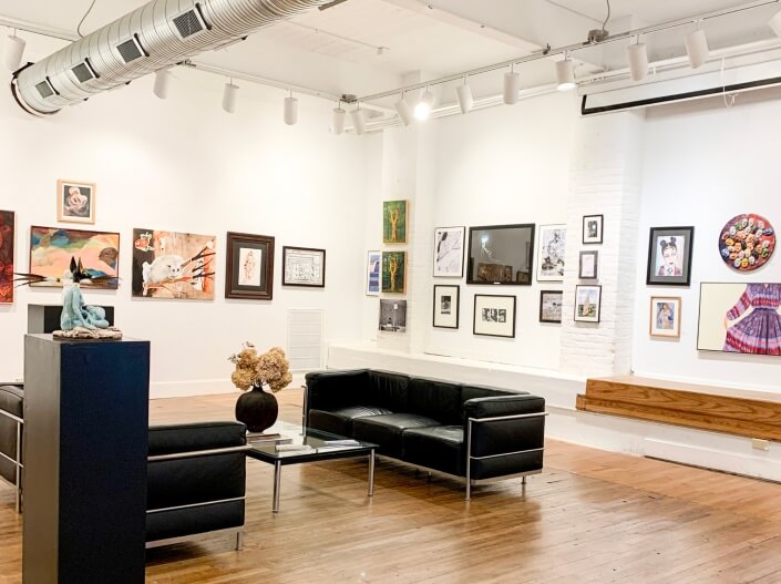 ASK's member's gallery with art hanging on the walls, with two couches and a coffee table