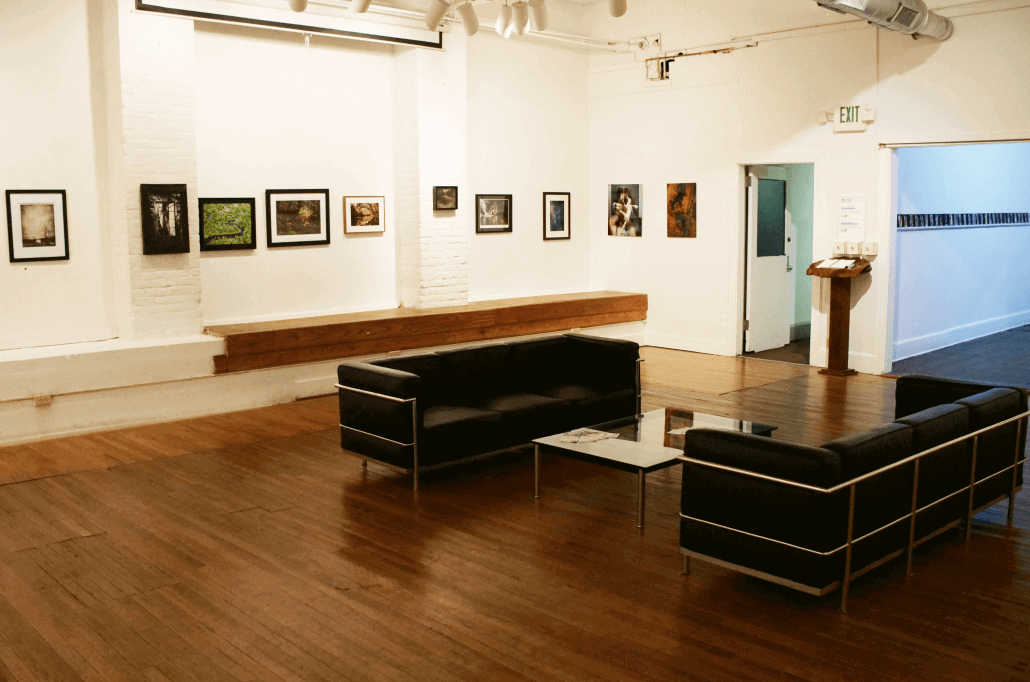 ASK's member's gallery with art hanging on the walls, with two couches and a coffee table