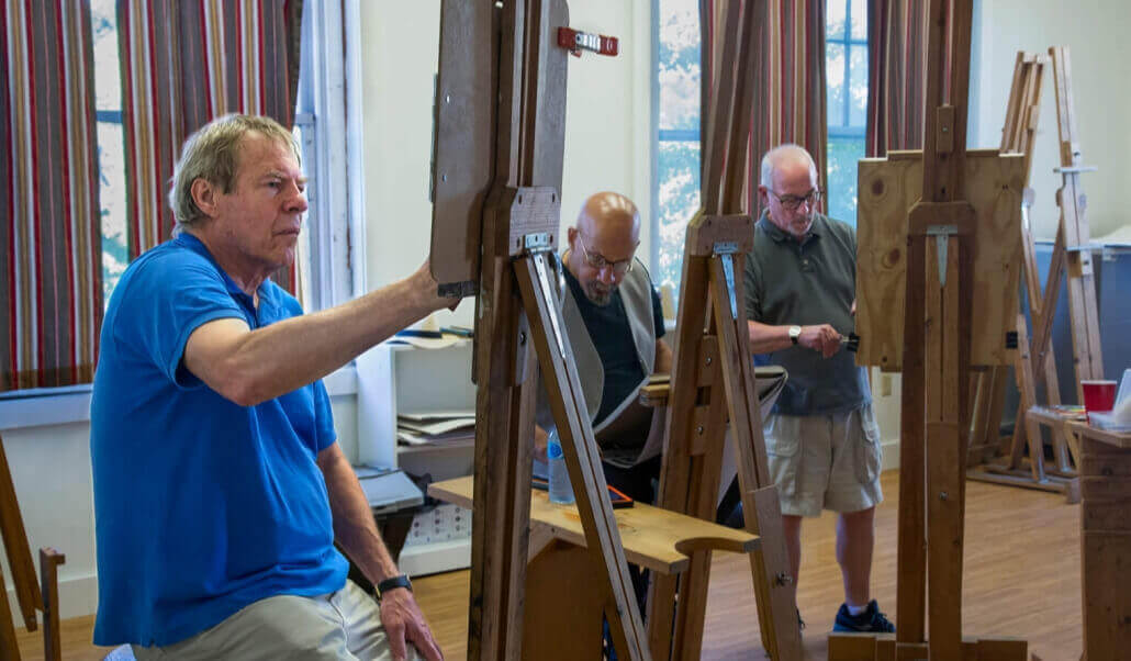 a group of older men in a drawing class with easels