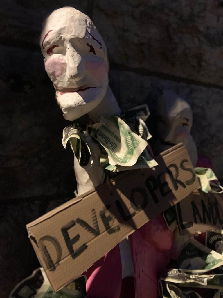 a photograph of a puppet holding a cardboard sign that reads "developers"