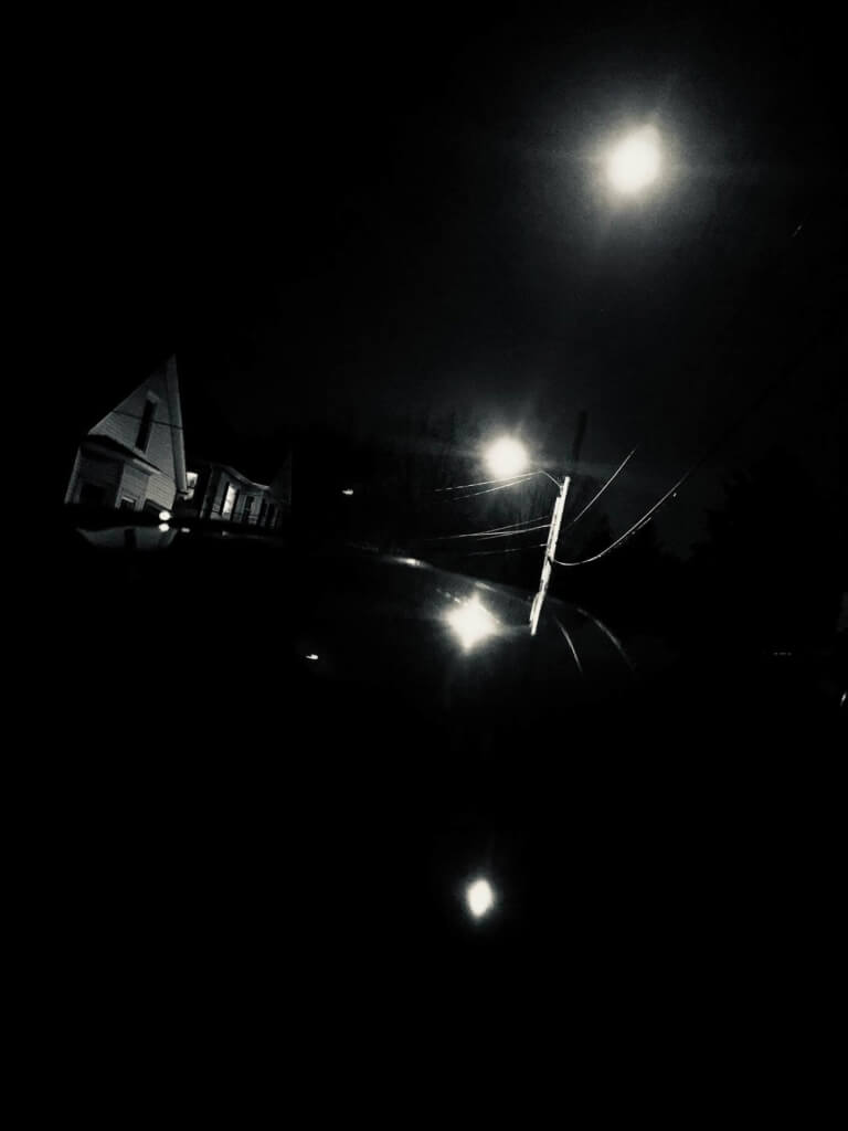 a dark photograph taken at night, showing streetlights and reflections