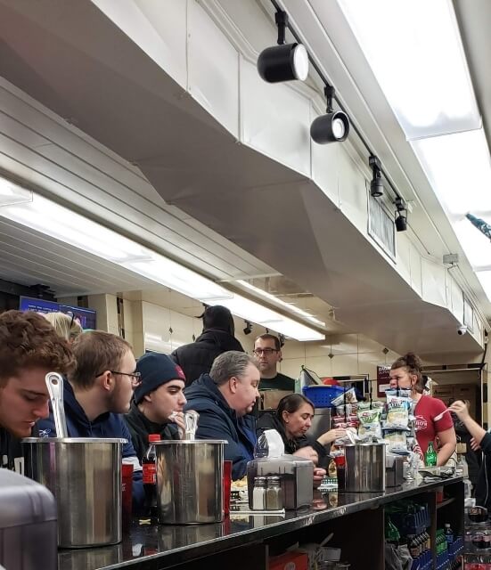 A group of cheesesteak eaters sitting at the counter at D'allisandros Steaks in Philadelphia